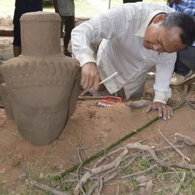 Một nhà khảo cổ đang làm sạch tượng sa thạch mới tìm thấy ở Siem Reap, Campuchia