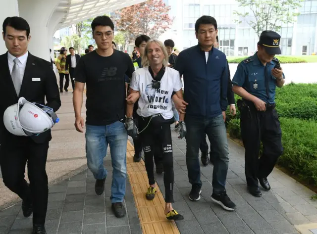 French urban climber Alain Robert (C) is arrested after being intercepted during his climb of the Lotte World Tower in Seoul on June 6, 2018