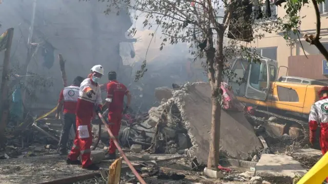 Equipes de resgate iranianas trabalham no local de um prédio danificado, após ataques israelenses, em Teerã, Irã (13 de junho de 2025)