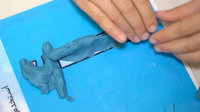 صورة تُظهر تمريناً حسياً عبر استخدام معجون أزرق اللون لرسم حرف الألف بالعربية.