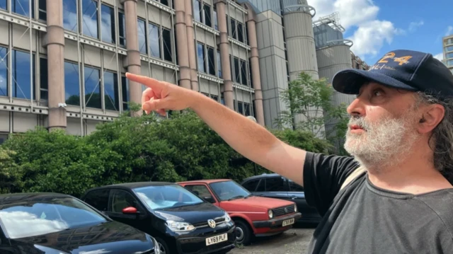 مارک نایگیت، ساکن محلی، با انگشت به ساختمانی اشاره می‌کند