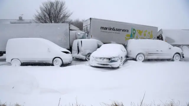Several trucks and cars, covered with snow, stand deserted after a pileup on February 27, 2018 near Sjobo, southern Sweden.