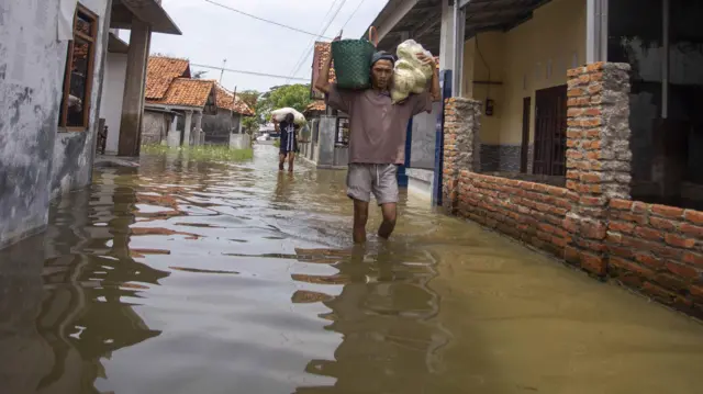 Warga melintasi banjir yang merendam permukiman di Desa Melakasari, Gebang, Kabupaten Cirebon, Jawa Barat, Kamis (7/3