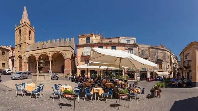 Praça com campanário e restaurante ao ar livre na Itália