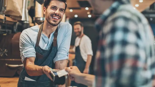 Imagem mostra vendedor sorrindo enquanto recebe pagamento7games instalar o aplicativo decliente com cartão7games instalar o aplicativo decrédito