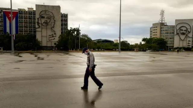 Un hombre con mascarillas camina por una calle vacía de La Habana.