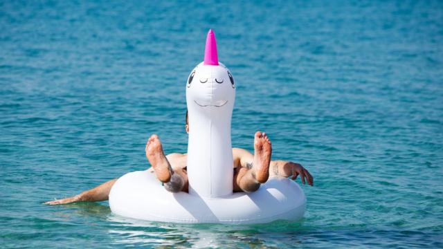 Hombre flotando en un inflable de unicornio