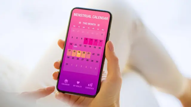 Ecran de telefon cu un calendar de monitorizare a ciclului menstrual.
