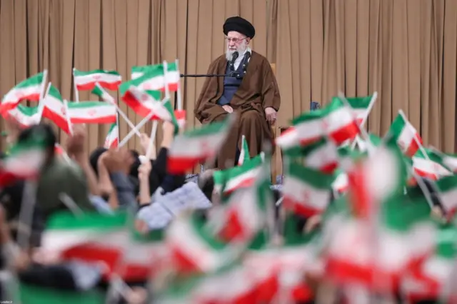 Ayatollah Ali Khamenei devant un auditoire agitant des drapeaux iraniens