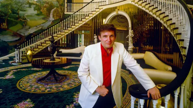 Donald Trump, vestido com uma camisa vermelha e um blazer branco, posa para fotobet1000 sportum enorme e imponente corredor embet1000 sportmansão.