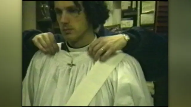 Молодий чоловік у білому церковному одязі з розпʼяттям на шиї