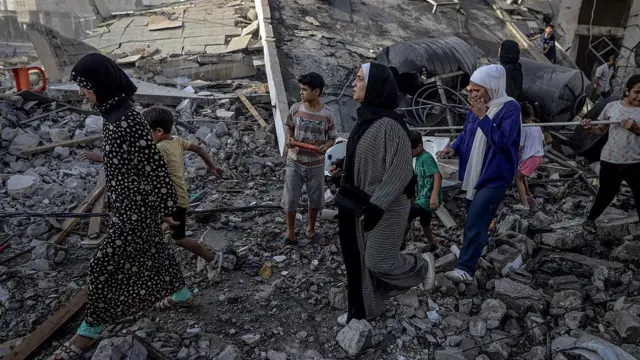 Women and children, walking on debris, leave the area following the Israeli attack on Omar al-Mukhtar Street of Gaza City, Gaza on 3 October 2025.