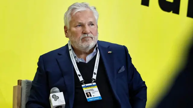 Александр Квасневський перед мікрофоном на жовтому тлі