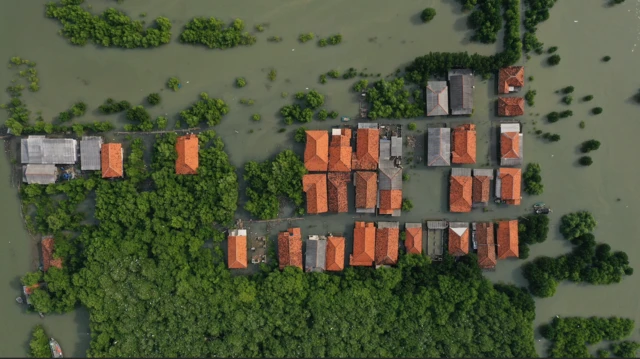 Suwandi dan istrinya, Watini, difoto di ruang tamu mereka yang terendam air rob.