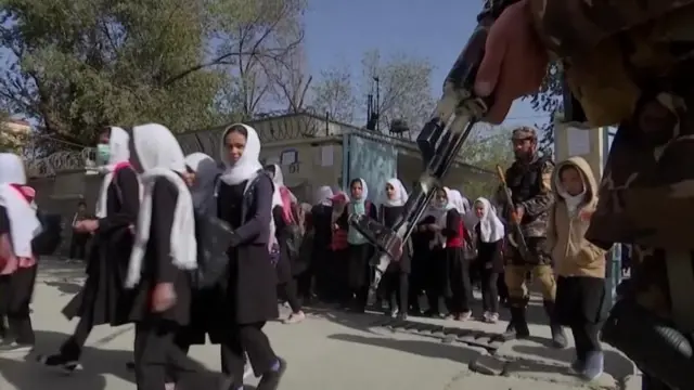 کوچنۍ نجونې په داسې حال کې ښوونځي ته ځي چې د طالبانو وسله وال یې څنګ ته لیدل کېږي