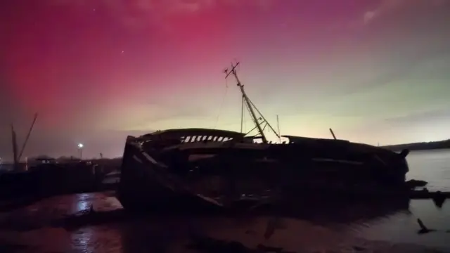 A pink haze frames an overturned ship in Pin Mill, Suffolk
