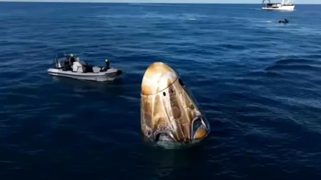 Cápsula no mar, com bote ao lado 