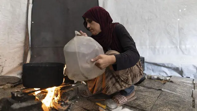 Gazzeli bir kadın bir çadır önünde su kaynatıyor