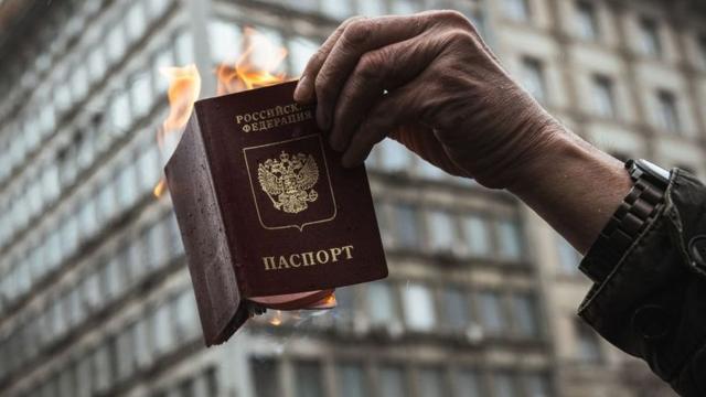 Un hombre quema un pasaporte ruso en protesta en la guerra.