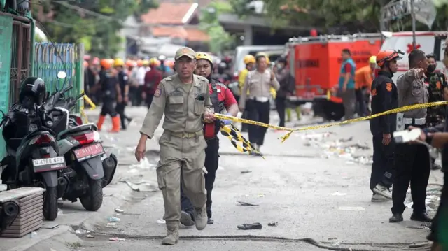 Petugas membawa garis polisi saat terjadi getaran di Pondok Pesantren (Ponpes) Al Khoziny, Kecamatan Buduran, Sidoarjo, Jawa Timur, Selasa (30/9/2025).