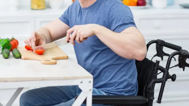 Un hombre en silla de ruedas cortando comida