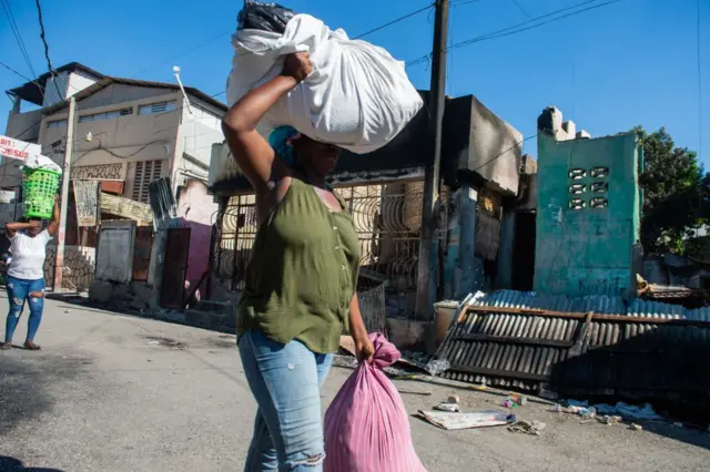 Obinrin kan to n rin lọ laarin igboro kan to da paroparo gbe ẹru lori fa apo ẹru miran, bi ẹni to n fi ilu silẹ.