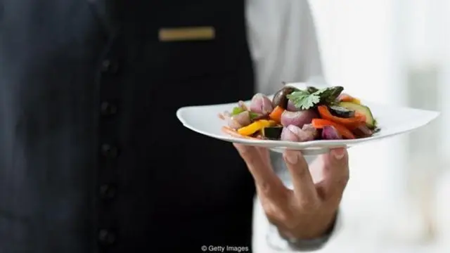 प्लेट में खाना लेकर जाता एक शख़्स