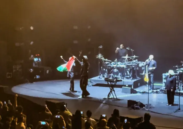Robert Del Naja and Grant Marshall from Massive Attack stand with a Palestinian flag onstage at the end of their performance in Singapore, July 29, 2026, in this screengrab from video obtained from social media. Two members of Massive Attack were issued with stern warnings and barred from re-entering Singapore after the British band ended their performance on Wednesday with a display of the Palestinian flag, police said. Simran Panaech/via REUTERS THIS IMAGE HAS BEEN SUPPLIED BY A THIRD PARTY. MANDATORY CREDIT. NO RESALES. NO ARCHIVES. THIS PICTURE WAS CROPPED BY REUTERS TO ENHANCE QUALITY. AN UNCROPPED VERSION HAS BEEN PROVIDED SEPARATELY.