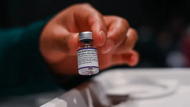 Una mano sosteniendo una dosis de la vacuna de Pfizer.