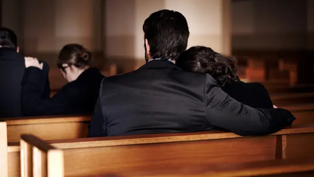 A woman being comforted at a funeral