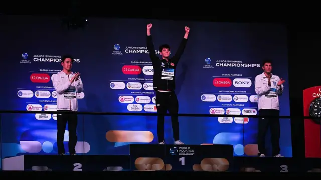 Kuzey Tunçelli Romanya'daki dünya şampiyonasında podyumda zaferini kutluyor. Yanında gümüş ve bronz madalya alan yüzücüler de var.