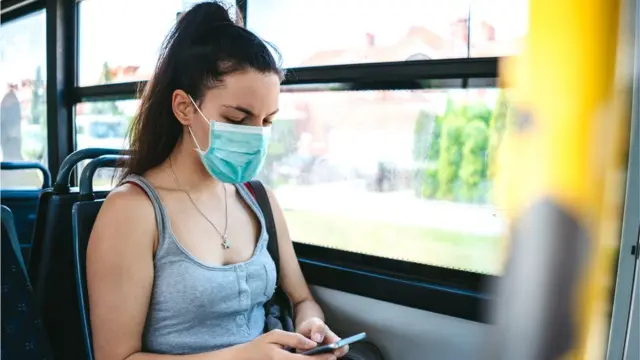 Mulher usando máscara num ônibus