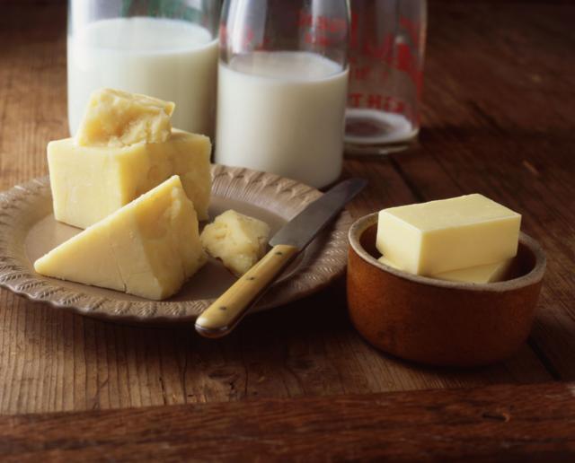 Leite, queijo e manteiga postos sobre uma mesa de madeira