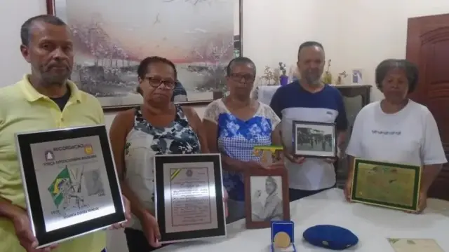 Integrantes da família segurando recordações emolduradas