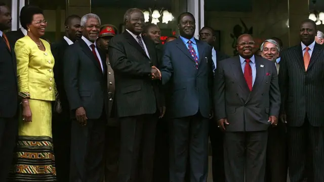 Kiongozi wa upinzani nchini Kenya Raila Odinga (wa tatu kutoka kulia) akiwa anapeana mkono na Rais Mwai Kibaki (wa tatu kutoka kushoto) huku aliyekuwa Katibu Mkuu wa Umoja wa Mataifa Kofi Annan (wa pili kutoka kushoto) na hayati Benjamin Mkapa (wa pili kutoka kulia) akiwa pembeni yao wakati wa mkutano na waandishi wa habari nje ya ofisi ya Rais tarehe 24 mwezi Januari 2008 jijini Nairobi, Kenya. Mkutano huu ulikuwa wa kwanza kati ya mahasimu wawili wa kisiasa tangu kuanza mzozo baada ya uchaguzi uliosababisha mauaji ya watu nchini humo.