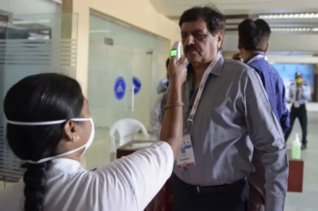 તાપમાન માપતાં મહિલા