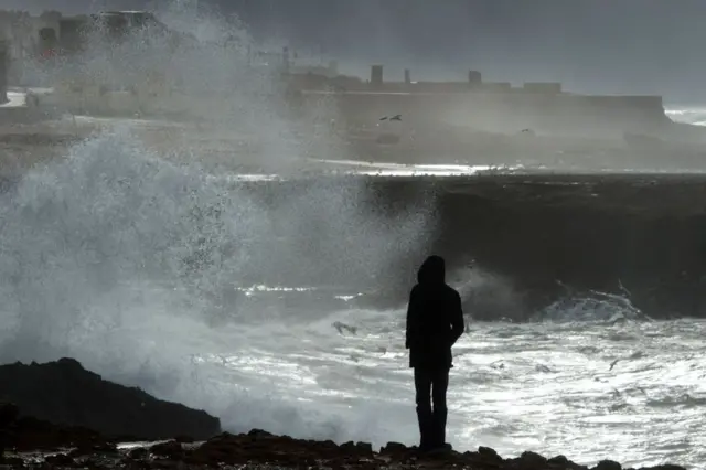 A Moroccan man walks along the coast during a storm in Rabat on January 8, 2018. Morocco has been facing an unusual cold wave for the past few days, with heavy snowfall in the mountainous regions and the installation of an anti-cold device in the most affected areas.
