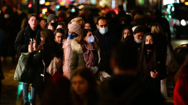 லண்டன் ஆக்ஸ்போர்டு தெருவில் கிறிஸ்துமசுக்கு முன்பாக பொருள்களை வாங்குவதற்கு முக கவசத்தோடு செல்லும் மக்கள்.