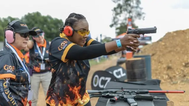 A woman wearing protective goggles and earmuffs shoots with a CZ Shadow 2 9mm pistol.