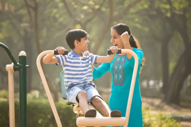 बागेत खेळणारा मुलगा आणि त्याची आई