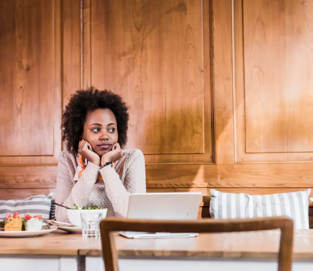 Une jeune femme dans un vêtement manches longues est à table avec des plats de nourriture devant elle.
