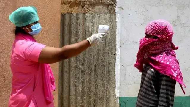 थर्मल स्केनिंग करती महिला स्वास्थ्यकर्मी