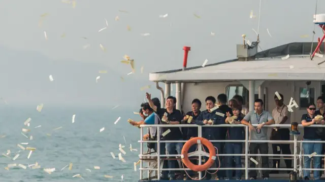 2012年10月4日，在香港南丫岛附近海域举行的渡轮碰撞事故罹难者悼念典礼上，哀悼者将纸钱抛入海中。