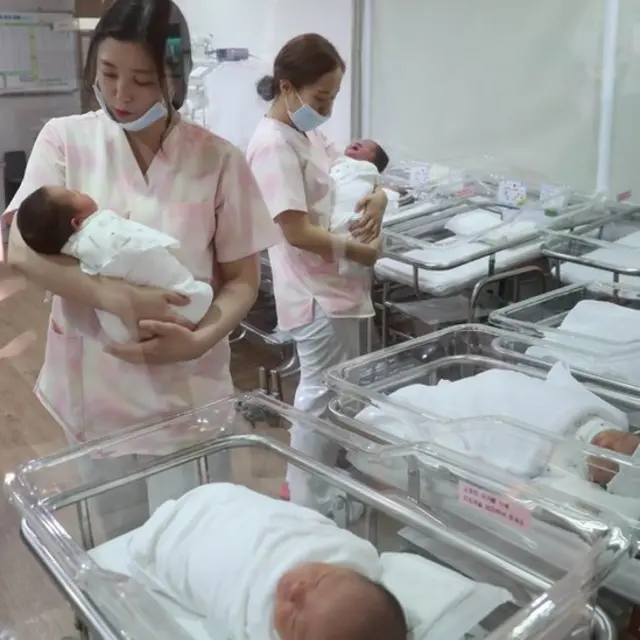 신생아실에서 간호사들이 아기들을 돌보고 있다