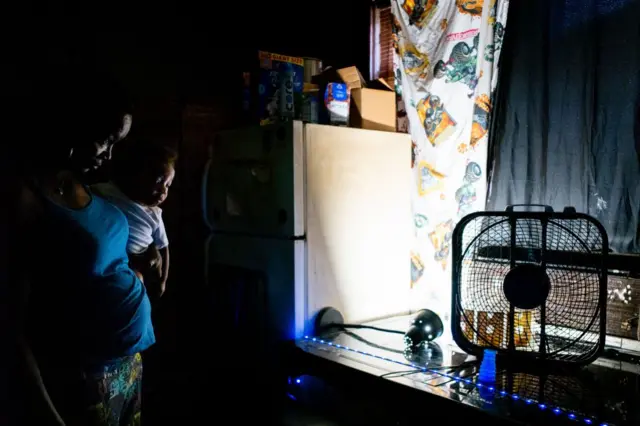 Yvette Johnson, yang akrab dipanggil Tootie, menggendong anaknya di dekat kipas jendela di rumahnya saat gelombang panas terjadi pada 21 Juli 2022 di Houston, Texas.