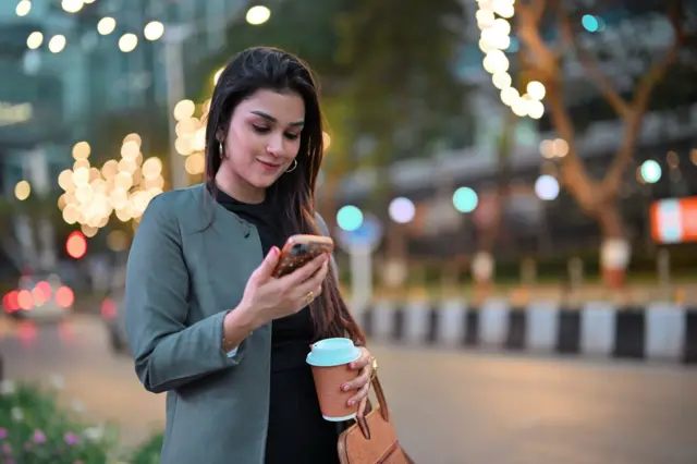 मोबाइल फ़ोन पकड़े महिला