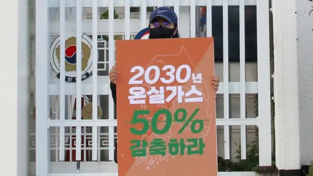 서울환경운동연합 회원이 14일 서울 정부서울청사 앞에서 온실가스 감축을 촉구하고 있다