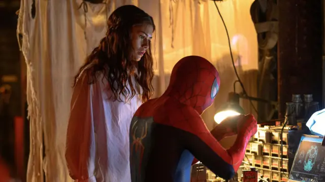 Una foto de publicidad de "Spiderman: un nuevo día" muestra a Zendaya en el papel de MJ observando a Spiderman manipulando un artefacto frente a un computador