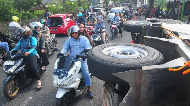 Sejumlah pengendara sepeda motor melintas di samping mobil yang mengalami kecelakaan