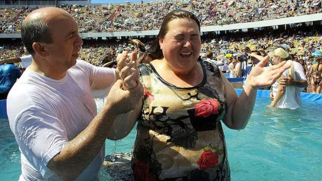 Una mujer participa de un bautizo masivo.